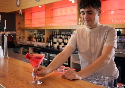 Friendly staff member serving a pink cocktail